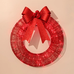 Macro detail of red glitter tinsel Christmas wreath with warm LED lights and bow