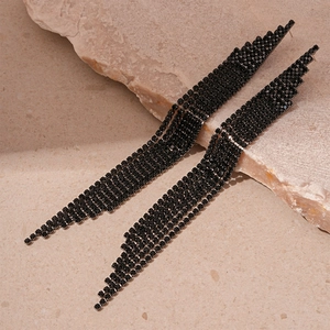 Détail de boucles d'oreilles noires à pampilles longues avec zircons géométriques
