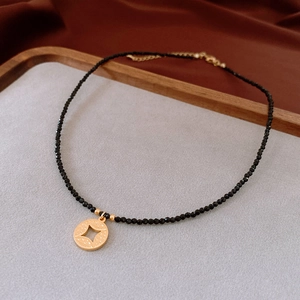 Detail of black beaded necklace with a golden star pendant on brown silk fabric