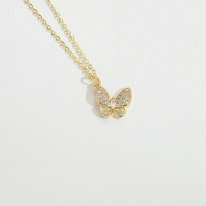 Macro shot of gold butterfly pendant necklace with sparkling crystals on white leather