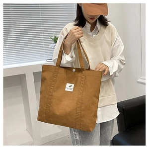Detailed view of brown corduroy tote bag featuring a snap button and woven label