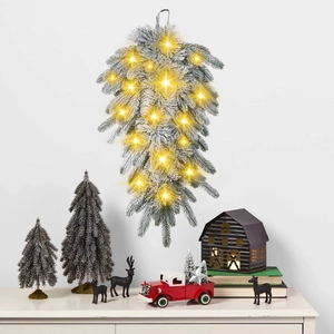 Frosted Christmas teardrop wreath with pine cones and warm LED lights on a white wall