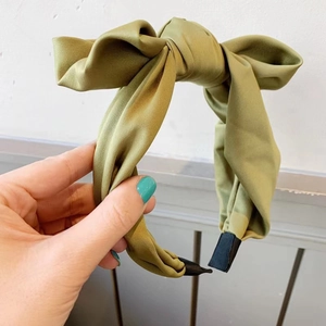 Detailed view of an olive green satin headband featuring a large elegant bow knot design