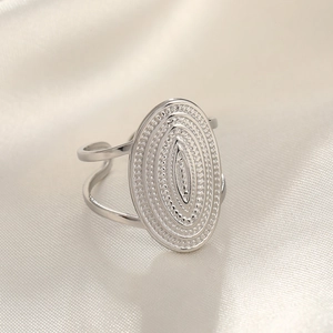 Macro detail of textured silver hammer pattern on wide oval stainless steel ring surface