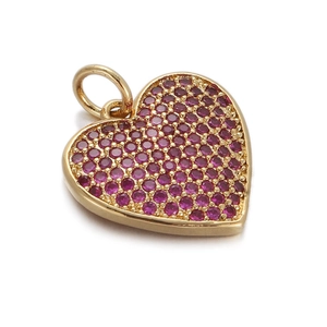 Close-up of golden heart pendant featuring sparkling pavé set magenta zircons on white background