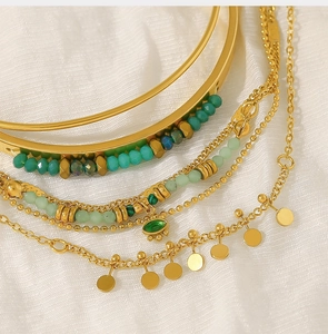 Detailed macro shot of a gold layered bracelet set with green stone beads and evil eye charm