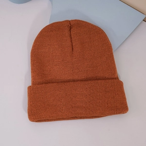 Detail view of deep orange knitted beanie showing soft ribbed texture and turn-up cuff design