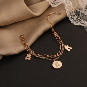 Close-up of double-layer rose gold chain bracelet with hollow bear charms on silk cloth