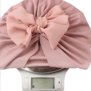 Detail shot of a lightweight pink baby turban hat weighing only 24.6g on a digital scale