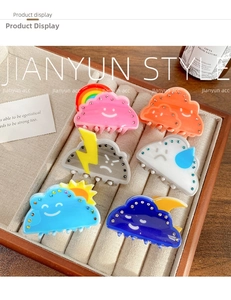 Detailed view of six acrylic weather-themed hair claws with rhinestones on a tray