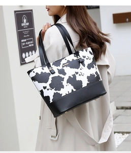 Close-up of black and white cow print leather tote bag with gold JINGPIN logo detail