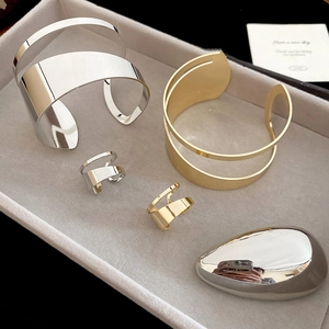 Detail of irregular hollow metal bangles and rings in gold and silver on a jewelry tray