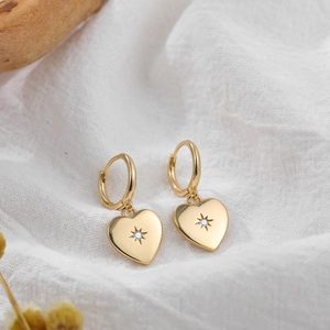 Macro shot of 18K gold plated heart earrings with starburst diamond on linen background