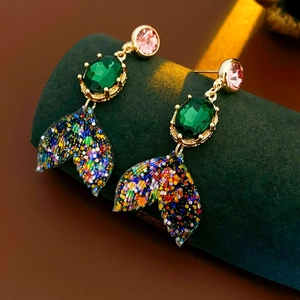 Gros plan de boucles d'oreilles sirène dorées avec cristaux sur un support d'exposition