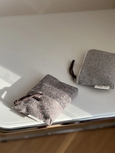 Close-up of grey herringbone tweed coin pouch with colorful speckles and zipper