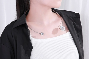 Close-up of a silver stainless steel open collar necklace featuring two large round crystals