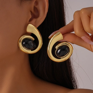 Détail d'une grande boucle d'oreille spirale dorée avec pierre noire ovale