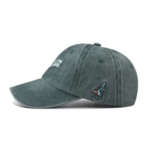 Detail of hummingbird embroidery and distressed cotton fabric on vintage green baseball cap