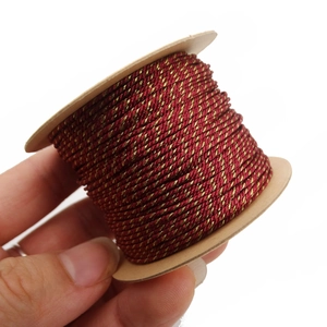 Macro shot of 1mm burgundy and gold metallic braided thread on a cardboard spool