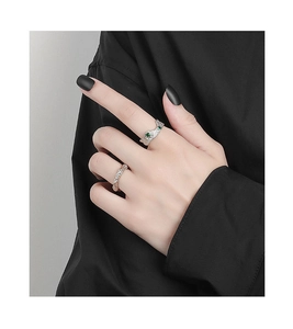 Primo piano di anello a rana in argento con pietre verdi e anello in oro rosa