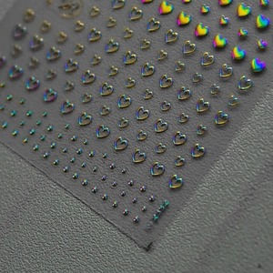 Macro detail of holographic heart and dot nail art stickers with metallic reflection