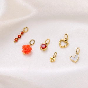Detailed view of six gold-plated heart pendants with beads and roses on beige silk