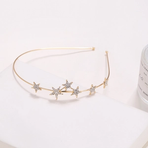 Elegant gold metal headband with sparkling rhinestone stars on a white stand