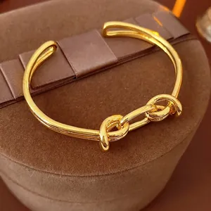 Gold plated oval knot cuff bracelet with a minimalist polished metal design on a velvet box