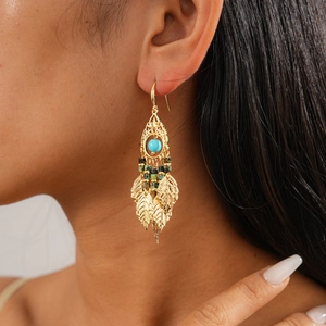 Gros plan sur des boucles d'oreilles feuille d'or vintage avec perles turquoise