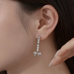 Macro shot of silver bow earring with sparkling cubic zirconia and long tassels