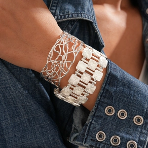 Macro detail of silver-finish hollow crisscross cuff and textured link bracelet set