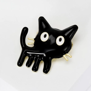 Close-up of cute black enamel cat brooch with gold metallic outlines and white eyes