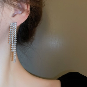 Close-up of sparkling silver tassel earrings with zircon stones worn by a model