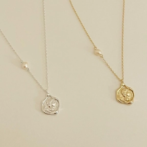 Detail of vintage coin pendant necklaces with relief portraits and white pearl accents