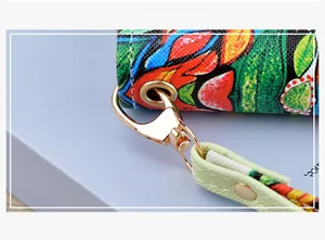 Detailed view of floral print wallet with light green leather handle and gold hardware