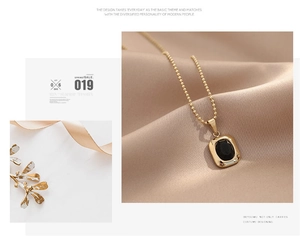 Detail of gold bead chain necklace with rectangular black onyx pendant on silk fabric