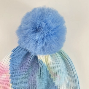 Winter tie-dye knit beanie featuring a large blue faux fur pom-pom and ribbed texture