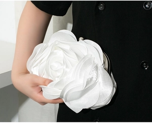 Close-up of elegant white 3D rose flower evening clutch with satin petals and metal clasp