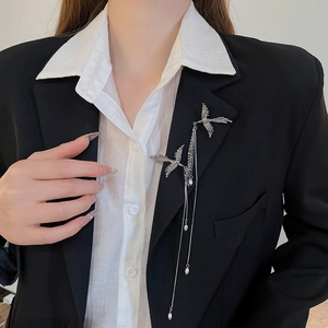 Detail of silver phoenix brooch with long tassels and pearls on black suit lapel