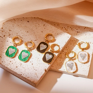 Detailed shot of retro heart earrings with green, black and white zircons on a stone base