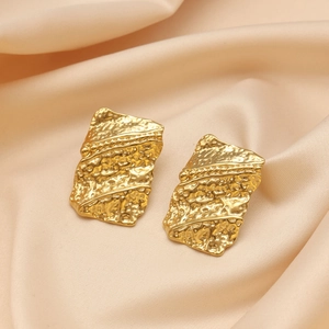Macro shot of 18K gold plated earrings with irregular hammered texture on silk