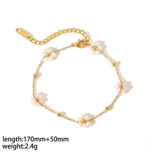 Detailed view of flower bracelet with white pearls and pink gemstones in gold finish
