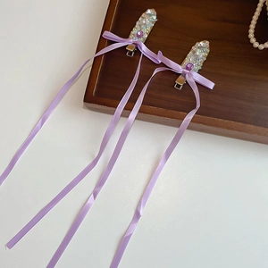 Detail of purple ribbon hair clips with shimmering rhinestones and silk streamers