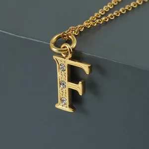 Vue macro détaillée du pendentif lettre F plaqué or 18 carats orné de trois zircons blancs