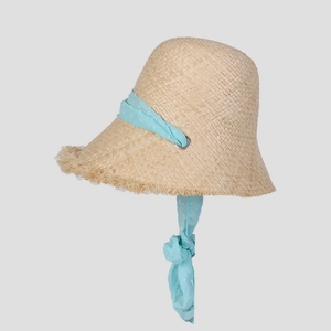 Detailed macro of raffia straw hat with raw frayed edges and blue polka dot ribbon ties