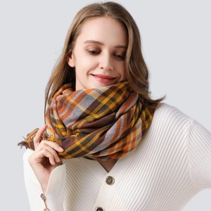 Plaid scarf in brown orange and grey pattern worn by model on studio background