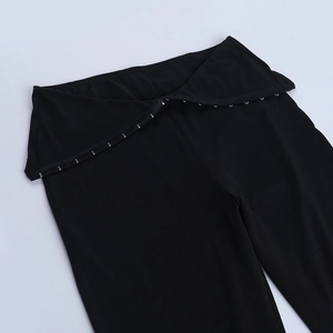 Dettaglio dei leggings a zampa neri a vita alta con chiusura a gancio argentata