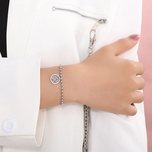 Dettaglio del bracciale a sfere argentate con ciondolo albero della vita su una modella