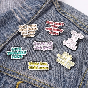 Set of 7 colorful enamel pins with inspirational quotes on a blue denim jacket background