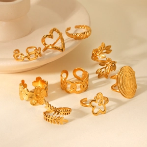 Set of 8 gold titanium steel rings featuring heart, leaf, and flower patterns on white porcelain